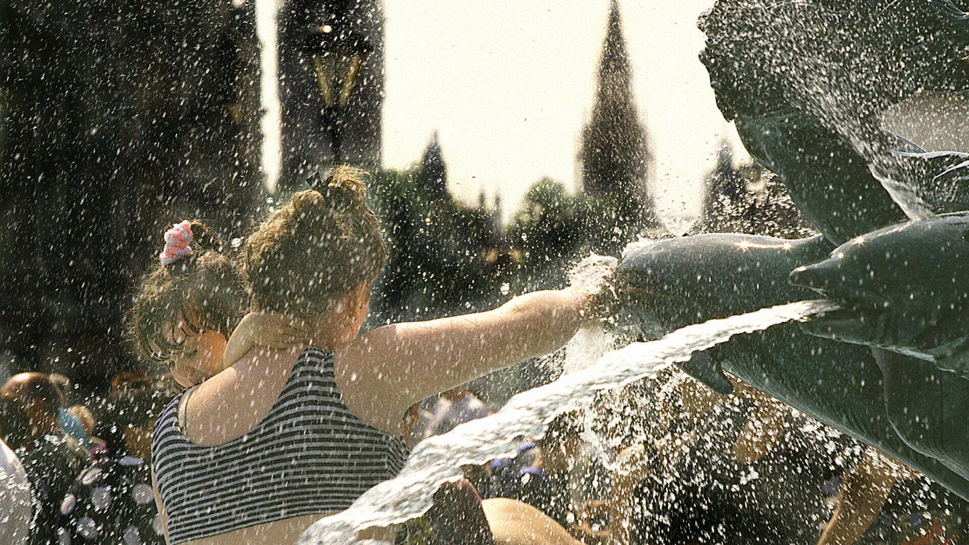 An unidentified mother gives her small child a freshening dip in one of the dolphin fountains in  London's Trafalgar square Saturday August 12, 1995 - Sputnik International, 1920, 15.09.2023
