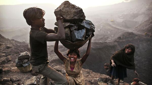 In this Jan. 6, 2011 file photo, a young woman stumbles as she tries to carry a large basket of coal as they illegally scavenge at an open-cast mine in the village of Bokapahari in the eastern Indian state of Jharkhand - Sputnik International