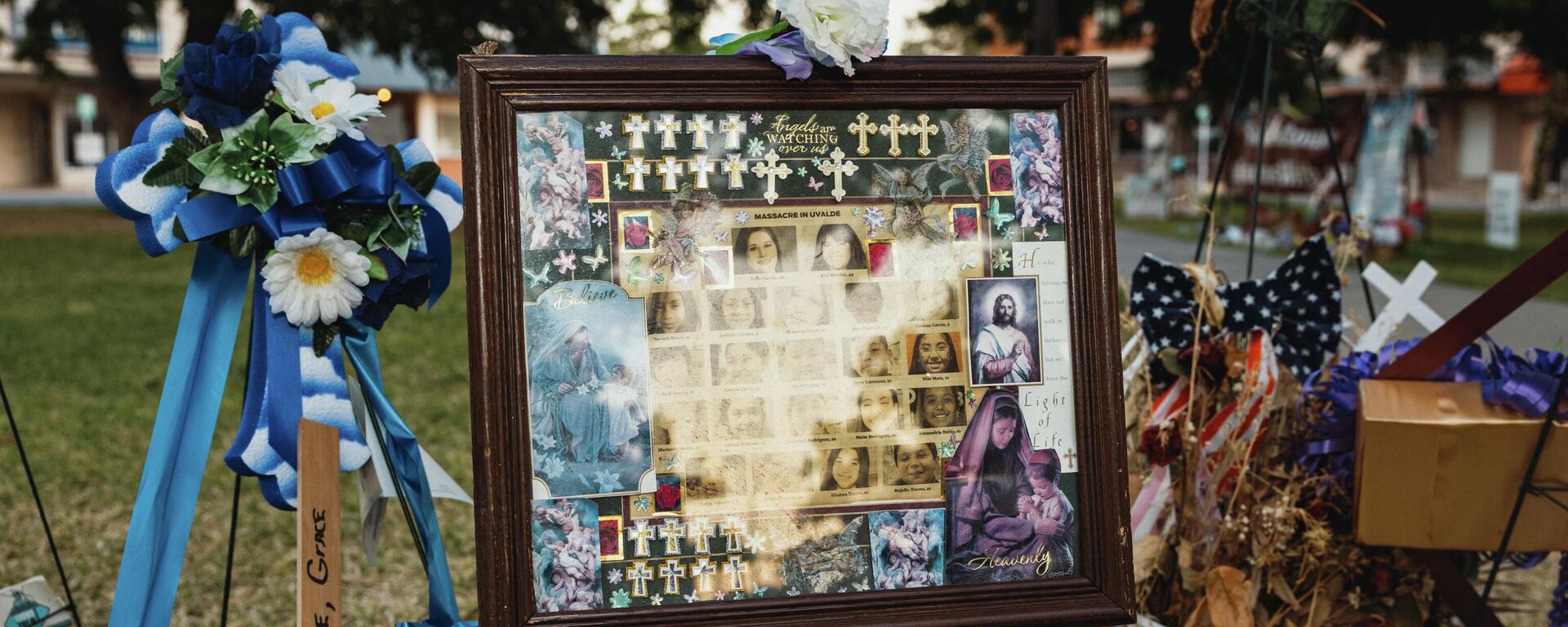 A framed picture is adorned with flowers and crosses at a memorial for the victims of the mass shooting at Robb Elementary School on June 25, 2022 in Uvalde, Texas. The Uvalde community is marking one month since the deadly shooting where 19 students and 2 teachers were killed.  - Sputnik International, 1920, 21.07.2022