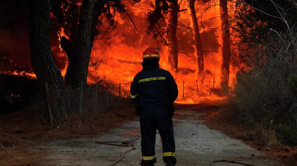 A firefighter tries to extinguish a forest fire near the beach resort of Vatera, on the eastern Aegean island of Lesvos, Greece, on Saturday, July 23, 2022. People were evacuated on Saturday as a wildfire threatened properties near a beach in the southern part of the island, which is also a popular tourist attraction. - Sputnik International