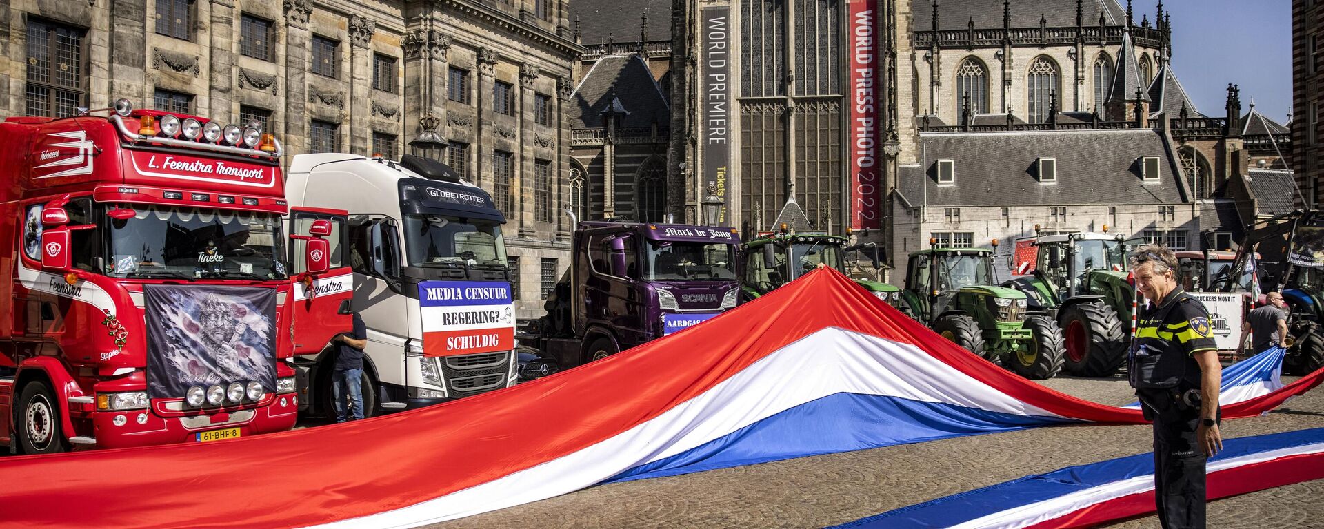 A Dutch police officer looks on at two Dutch national flags with trucks and tractors in the background during a rally of the Netherlands In Resistance group sympathizers to support farmers, fishermen and truckers, on Dam Square in Amsterdam on July 23, 2022.  - Sputnik International, 1920, 16.08.2022