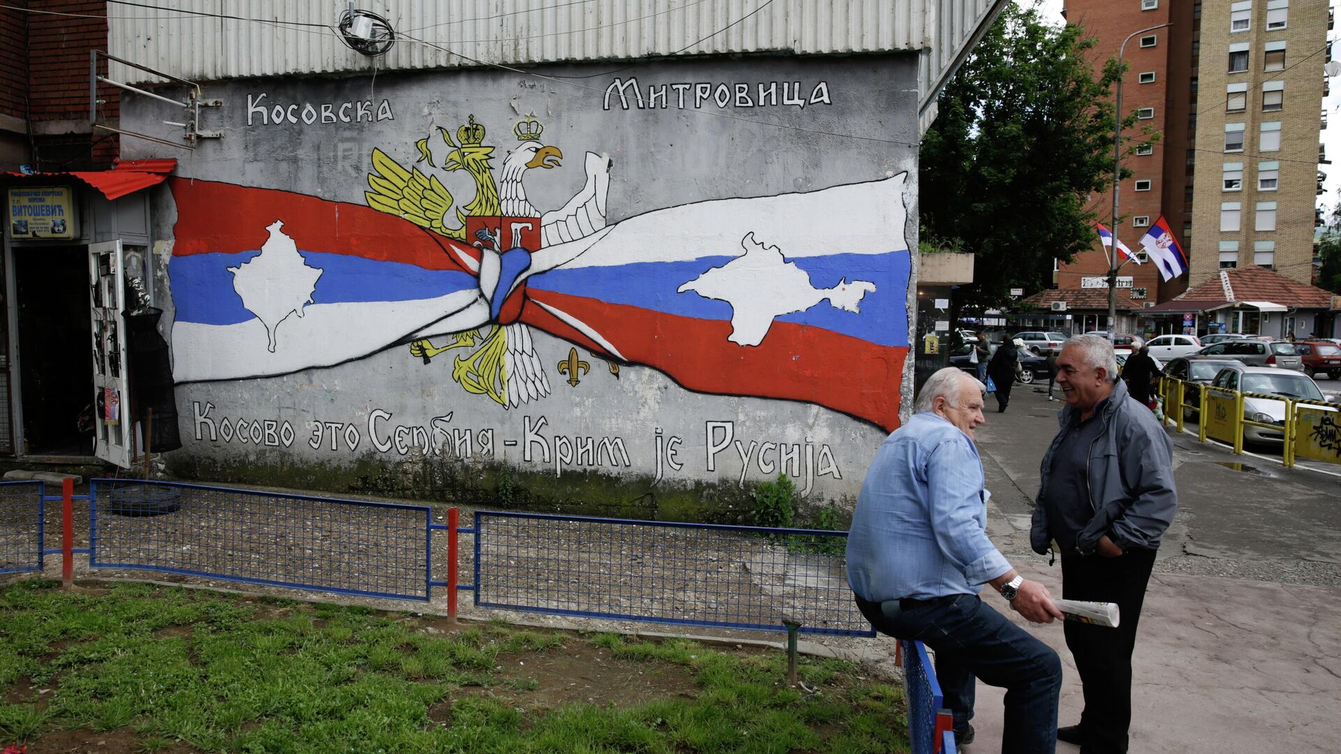 People rest next to the graffiti reading Kosovo is Serbia, Crimea is Russia, in Kosovska Mitrovica, Serbia.  - Sputnik International, 1920, 01.08.2022