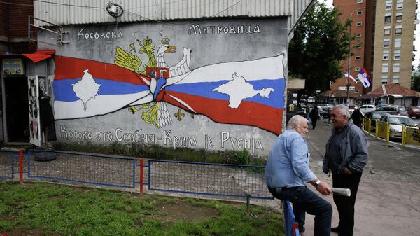 People rest next to the graffiti reading Kosovo is Serbia, Crimea is Russia, in Kosovska Mitrovica, Serbia.  - Sputnik International