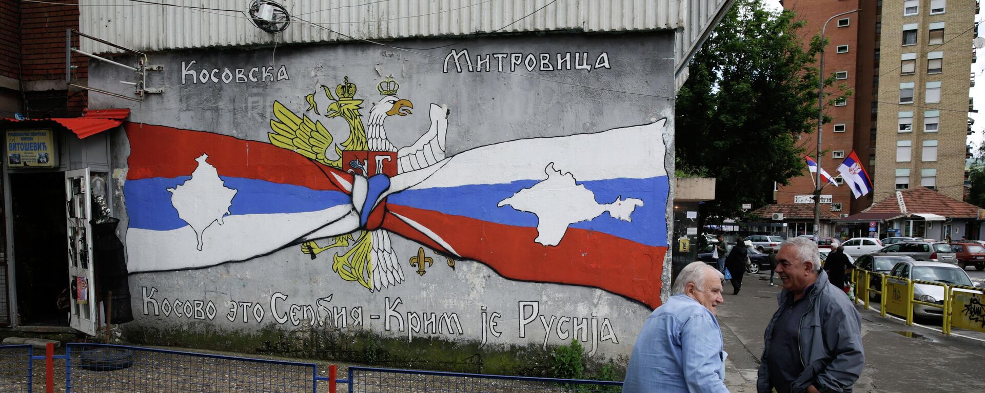 People rest next to the graffiti reading Kosovo is Serbia, Crimea is Russia, in Kosovska Mitrovica, Serbia.  - Sputnik International, 1920, 31.07.2022