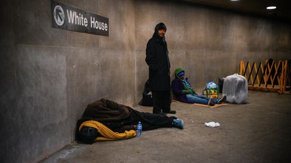 A homeless person sleeps below a sign indicating the exit to the White House at McPherson Square Metro station in Washington, DC - Sputnik International