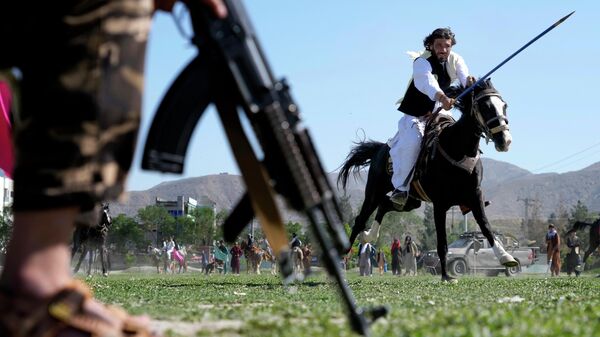 An Afghan man rushes to the target with his horse as a Taliban fighter stands guard during a spear racing in the sprawling Chaman-e-Huzori park in downtown Kabul, Afghanistan, Friday, May 6, 2022 - Sputnik International