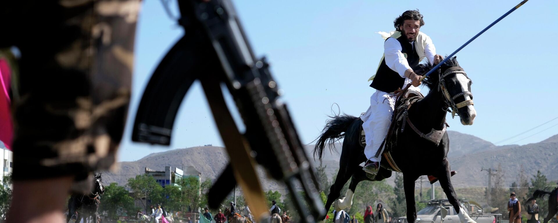 An Afghan man rushes to the target with his horse as a Taliban fighter stands guard during a spear racing in the sprawling Chaman-e-Huzori park in downtown Kabul, Afghanistan, Friday, May 6, 2022 - Sputnik International, 1920, 03.08.2022