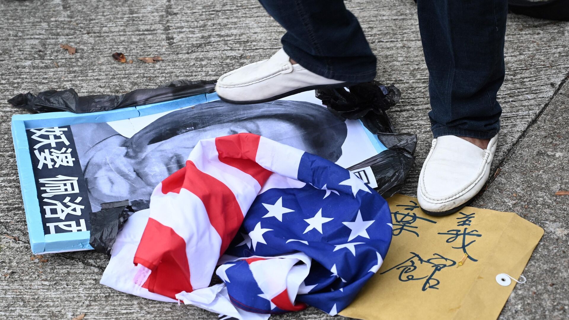 A pro-Beijing protester stamps on an image depicting the US House Speaker Nancy Pelosi and the US flag at a protest outside the US Consulate in Hong Kong on August 3, 2022 after Pelosi arrived in Taiwan late on August 2, 2022 as part of a tour of Asia that has inflamed tensions between the US and China.  - Sputnik International, 1920, 06.08.2022