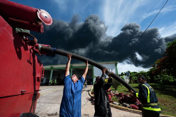 Firefighters work near the massive fire at a fuel depot which was sparked by a lightning strike in Matanzas, Cuba on August 8, 2022.  - Sputnik International