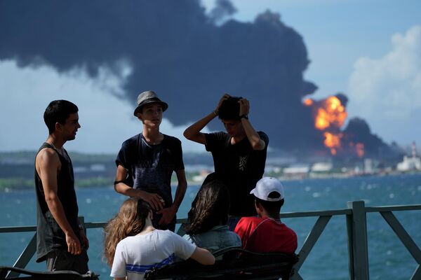 Youth gather on a dock while flames and smoke continue to rise from the Matanzas Supertanker Base, as firefighters and specialists work to quell the blaze, which began during a thunderstorm the night before, in Matazanas, Cuba, Saturday, August 6, 2022.  - Sputnik International