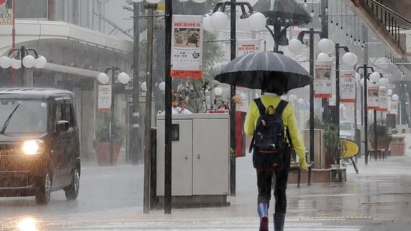 A pedestrian crosses the street during a downpour in the centre of Shizuoka, Shizuoka prefecture on the south coast of Japan on August 13, 2022, as heavy rains brought by Tropical Storm Meari hit the area. - Sputnik International