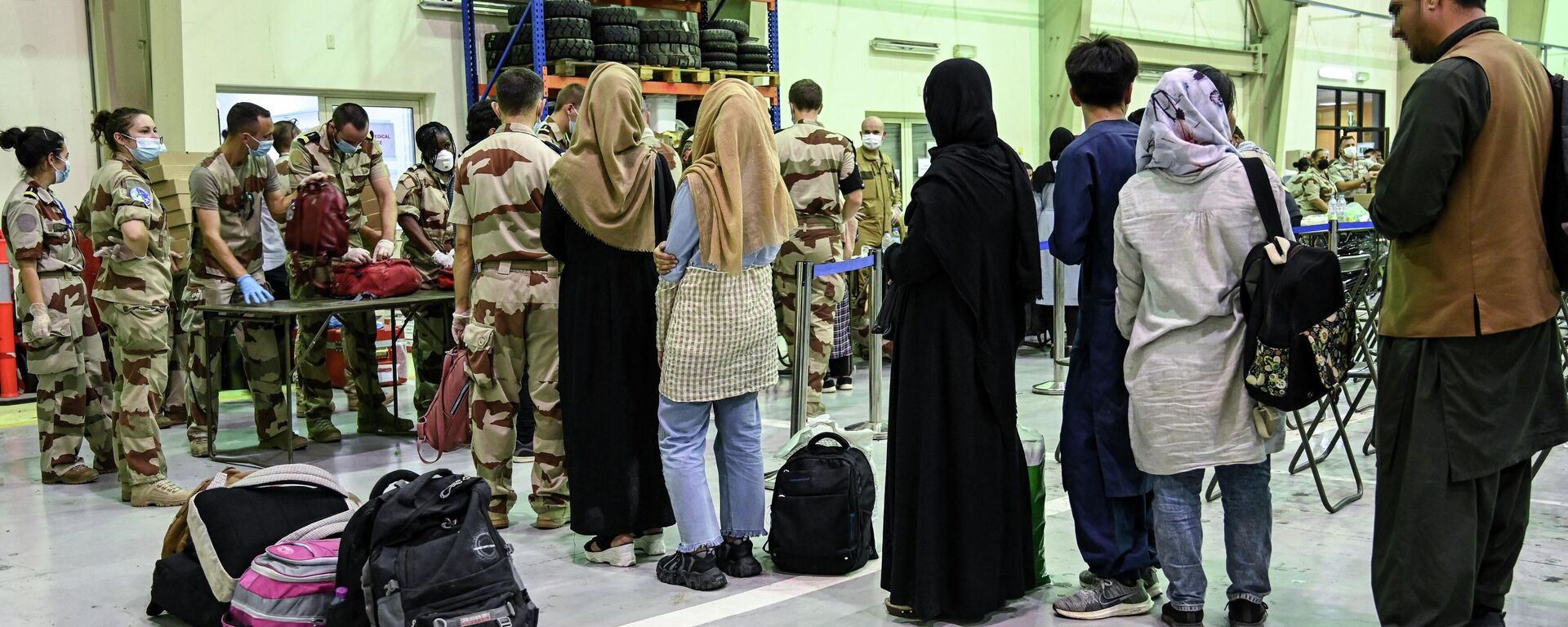 In this file photo taken on August 23, 2021 People wait to have their luggages checked by soldiers in a reunion and evacuation center at the French military air base 104 of Al Dhafra, near Abu Dhabi, after being evacuated from Kabul as part of the operation Apagan. - Sputnik International, 1920, 13.08.2022