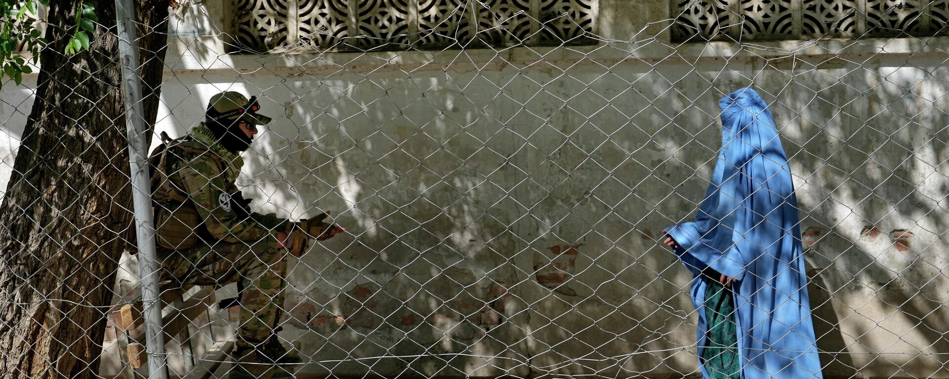 A Taliban fighter stands guard as a woman enters the government passport office, in Kabul, Afghanistan, Wednesday, April 27, 2022. Afghanistan's Taliban leadership has ordered all Afghan women to wear the all-covering burqa in public.  - Sputnik International, 1920, 09.09.2024