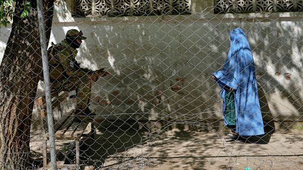 A Taliban fighter stands guard as a woman enters the government passport office, in Kabul, Afghanistan, Wednesday, April 27, 2022. Afghanistan's Taliban leadership has ordered all Afghan women to wear the all-covering burqa in public.  - Sputnik International