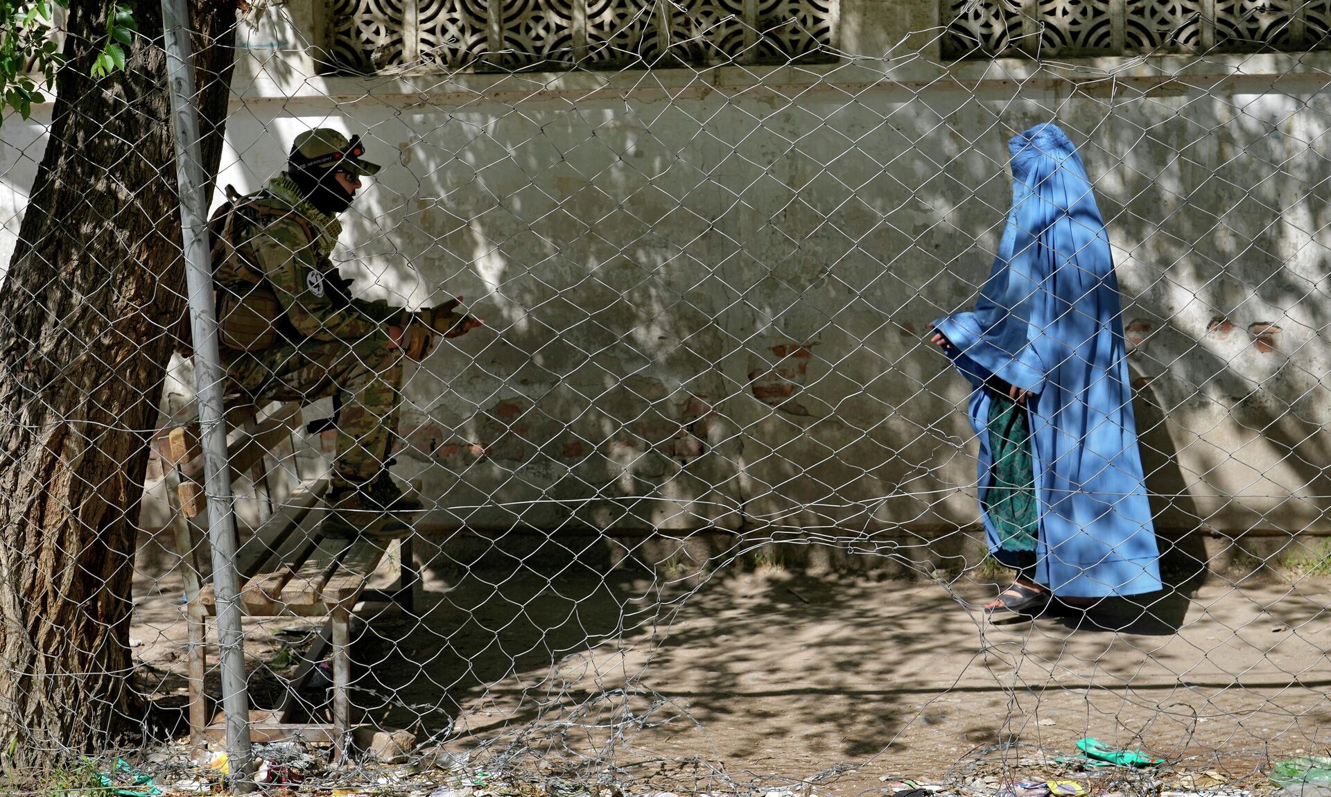 A Taliban fighter stands guard as a woman enters the government passport office, in Kabul, Afghanistan, Wednesday, April 27, 2022. Afghanistan's Taliban leadership has ordered all Afghan women to wear the all-covering burqa in public.  - Sputnik International, 1920, 25.12.2022