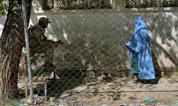 A Taliban fighter stands guard as a woman enters the government passport office, in Kabul, Afghanistan, Wednesday, 27 April 2022. Afghanistan&#x27;s Taliban leadership has ordered all Afghan women to wear the all-covering burqa in public. - Sputnik International