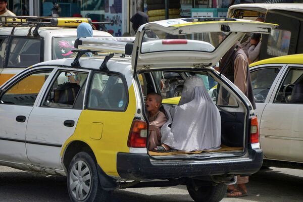 This photo taken on 19 July 2022, shows a woman and a child waiting in the back of a taxi to commute in Kandahar. - Sputnik International