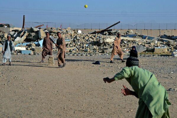 Boys play cricket in front of a school that was damaged during the conflict between the Taliban and Afghanistan&#x27;s former ruling government, in Kandahar on 12 May 2022. (Photo by Javed Tanveer/AFP) - Sputnik International