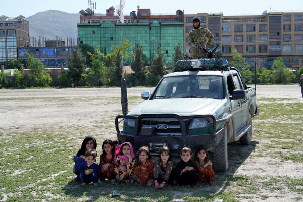 Afghan children watch a spear racing a horse as a Taliban fighter stands guard, in the sprawling Chaman-e-Huzori park in downtown Kabul, Afghanistan, on Friday, 6 May 2022. - Sputnik International