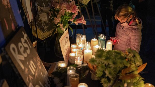A girl pays respects near a photo of cinematographer Halyna Hutchins, who was accidentally killed by a prop gun fired by actor Alec Baldwin, at a memorial table during a candlelight vigil in her memory in Burbank, California on October 24, 2021. - Sputnik International