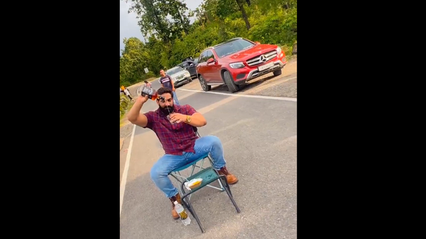 Screenshot from a video showing Indian YouTuber Bobby Kataria drinking alcohol while sitting on a chair in a middle of a busy road - Sputnik International