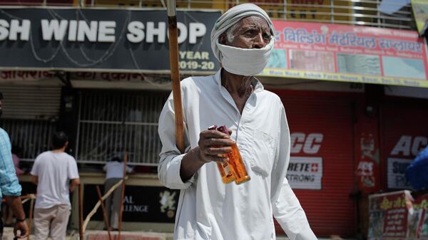 An elderly Indian man walks with two bottles of liquor purchased from one of the liquor shops which was reopened Monday after six weeks lockdown on the outskirts of New Delhi, India, Monday, May 4, 2020. - Sputnik International