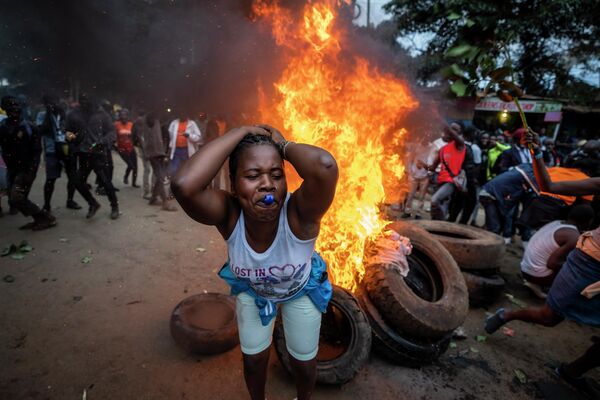 A supporter of presidential candidate Raila Odinga blows a whistle as she protests next to a roadblock of burning tires in the Kibera neighborhood of Nairobi, Kenya, August 15, 2022.  - Sputnik International