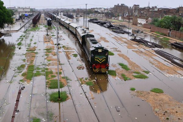 A train makes its way through a flooded railway track following heavy monsoon rains in Hyderabad, India, on August 18, 2022. - Sputnik International