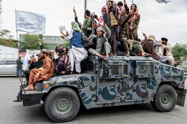 Taliban (under UN sanctions for terrorist activities) fighters hold weapons as they ride on a humvee to celebrate their victory day near the US embassy in Kabul on August 15, 2022.  - Sputnik International