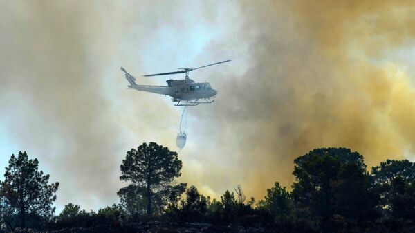 A helicopter drops water over a wildfire in Pinet, in the eastern Spanish region of Valencia, on August 7, 2018. - Sputnik International