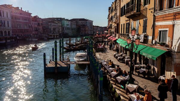 People sit at a restaurant's terrace in front of the Grand Canal in Venice, northeastern Italy, on January 11, 2022. - Sputnik International