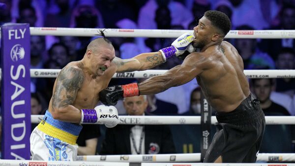 Britain's Anthony Joshua, right, takes a blow from Ukraine's Oleksandr Usyk during their world heavyweight title fight at King Abdullah Sports City in Jeddah, Saudi Arabia, Sunday, Aug. 21, 2022. - Sputnik International