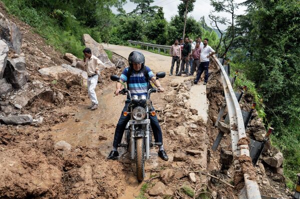 A motorcyclist tries to drive past mud and debris after a landslide blocked a road in Dharmshala, Himachal Pradesh state, India, Sunday, 21 August 2022. - Sputnik International