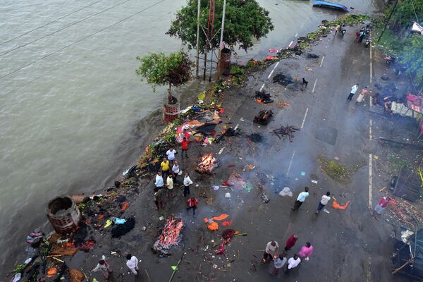 People gather beside funeral pyres along a street during monsoon rains in Allahabad on 21 August 2022. - Sputnik International