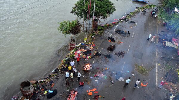 People gather beside funeral pyres along a street during monsoon rains in Allahabad on August 21, 2022. - Sputnik International