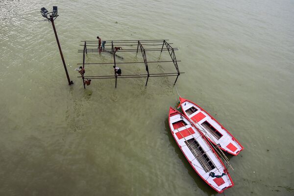 Youths sit on a submerged structure at Daraganj ghat before diving into the River Ganges after water levels rose in both the Ganges and Yamuna in Allahabad on 20 August 2022. - Sputnik International