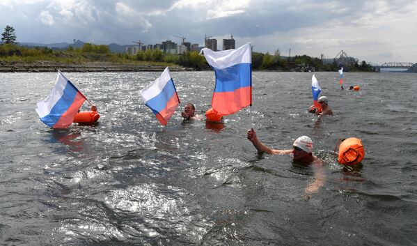 Ice swimmers during a 2,500-meter swimming marathon in Siberia&#x27;s Krasnoyarsk wave Russian tricolor flags. - Sputnik International