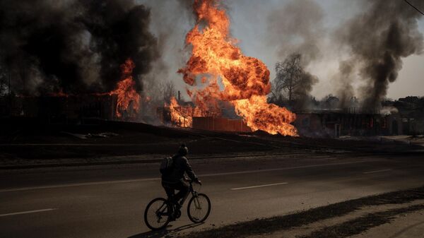 A man rides his bike past flames and smoke rising from a fire following an attack in Kharkiv, Ukraine, Friday, March 25, 2022. - Sputnik International