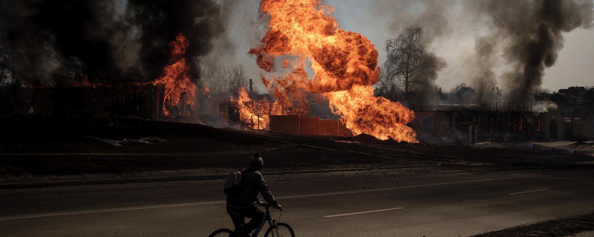 A man rides his bike past flames and smoke rising from a fire following an attack in Kharkiv, Ukraine, Friday, March 25, 2022. - Sputnik International, 1920, 23.08.2022