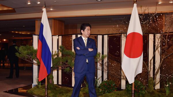 Japanese Prime Minister Shinzo Abe standing between flags of Russia, left, and Japan waits for the arrival of Russian President Vladimir Putin at a hot springs resort for their meeting in Nagato, Japan, Thursday, Dec. 15, 2016 - Sputnik International
