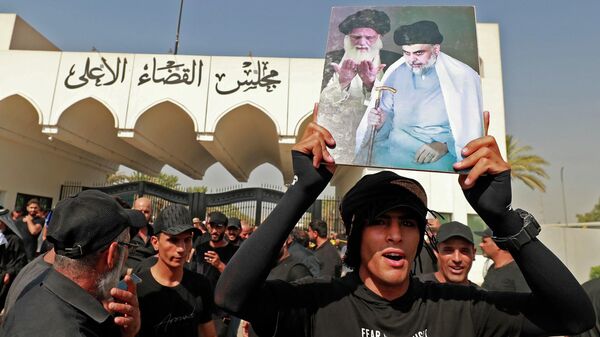 A man lifts a placard depicting Iraqi Shiite cleric Muqtada al-Sadr (R) and upporters of Iraqi Shiite cleric Muqtada al-Sadr his late father Grand Ayatollah Mohammed Sadeq al-Sadr, as his supporters gather outside the headquarters of the Supreme Judicial Council, Iraq's highest judicial body, in the capital Baghdad, on August 23, 2022.  - Sputnik International