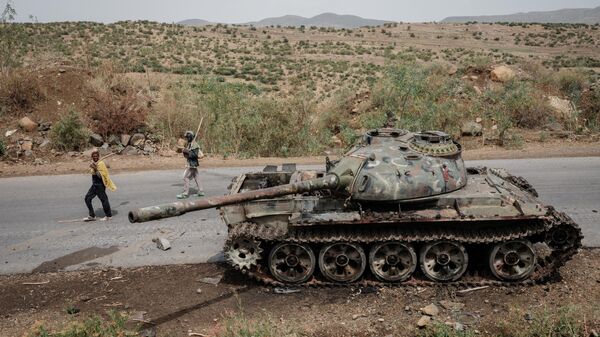 In this file photo taken on June 20, 2021 Local farmers walk next to a tank of alledged Eritrean army that is abandoned along the road in Dansa, southwest of Mekele in Tigray region, Ethiopia. - Sputnik International