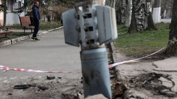 A man walks past an unexploded tail section of a 300mm rocket which appear to contained cluster bombs launched from a BM-30 Smerch multiple rocket launcher embedded in the ground after shelling in Lisichansk, LPR on April 11, 2022 - Sputnik International