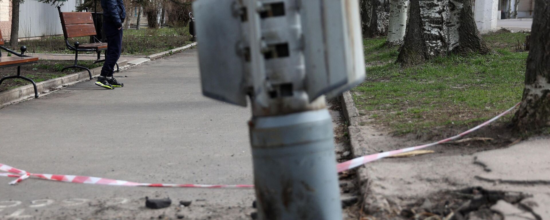 A man walks past an unexploded tail section of a 300mm rocket which appear to contained cluster bombs launched from a BM-30 Smerch multiple rocket launcher embedded in the ground after shelling in Lisichansk, LPR on April 11, 2022 - Sputnik International, 1920, 30.08.2022