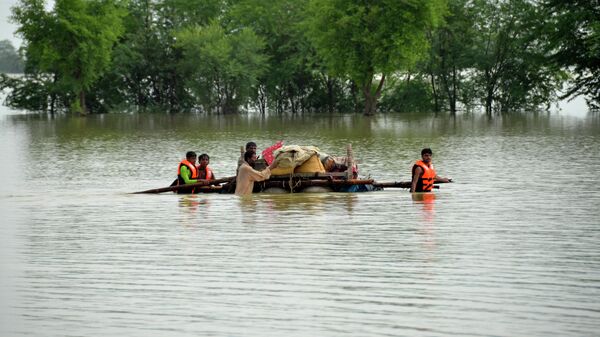 Displaced people transport usable belongings salvaged from their flood-hit home as they cross a flooded area in Sohbat Pur city of Jaffarabad, a district of Pakistan's southwestern Baluchistan province, Sunday, Aug. 28, 2022. - Sputnik International