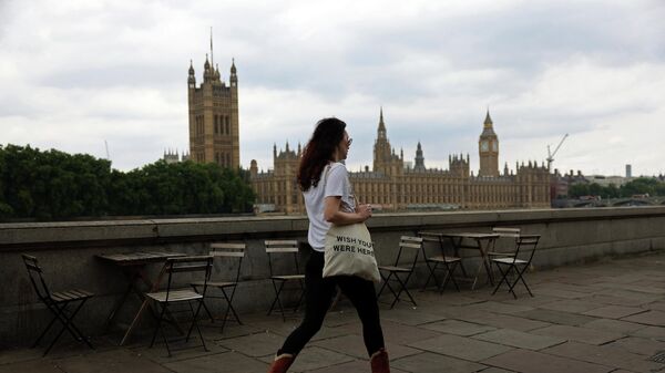 A pedestrian walks opposite The Palace of Westminster, Britain's Houses of Parliament - Sputnik International