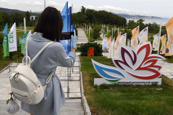A girl photographs a banner featuring the logo of the Eastern Economic Forum at the Far Eastern Federal University (FEFU) campus on Russky Island, Vladivostok. - Sputnik International