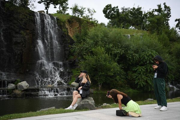 Girls taking photos in front of a waterfall at the Ajaks Bay in Vladivostok, ahead of the Eastern Economic Forum. - Sputnik International
