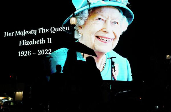 People pass by an image of Queen Elizabeth II projected onto a large screen at Piccadilly Circus, in London, Thursday, Sept. 8, 2022. Queen Elizabeth II, Britain&#x27;s longest-reigning monarch and a rock of stability across much of a turbulent century, died Thursday after 70 years on the throne. She was 96. - Sputnik International