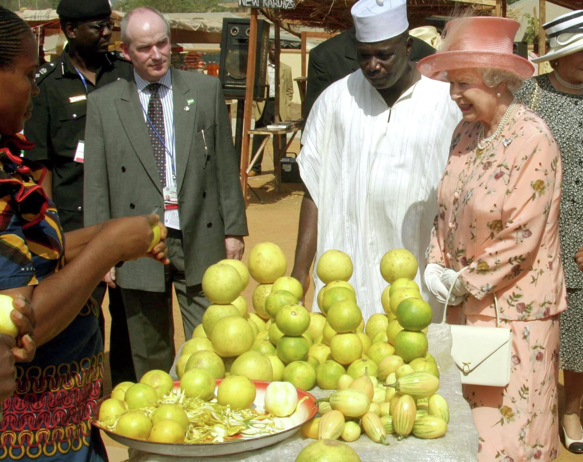 Britain's Queen Elizabeth II, right, tours a  mock-up market in the village of Karu in Nigeria, Thursday Dec. 4, 2003, on the second day of her official visit to the West African country during a meeting of British Commonwealth leaders. The market, staffed by a mixture of actual market-sellers and actors, was purpose-built for the event as part of a BBC radio soap-opera. (AP Photo/Ian Jones, POOL) - Sputnik International, 1920, 09.09.2022